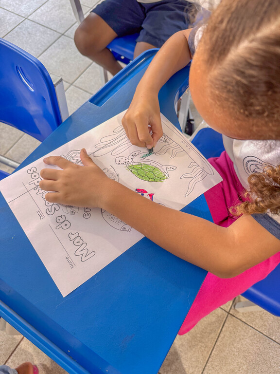 Criança colore uma atividade educativa sobre a vida marinha