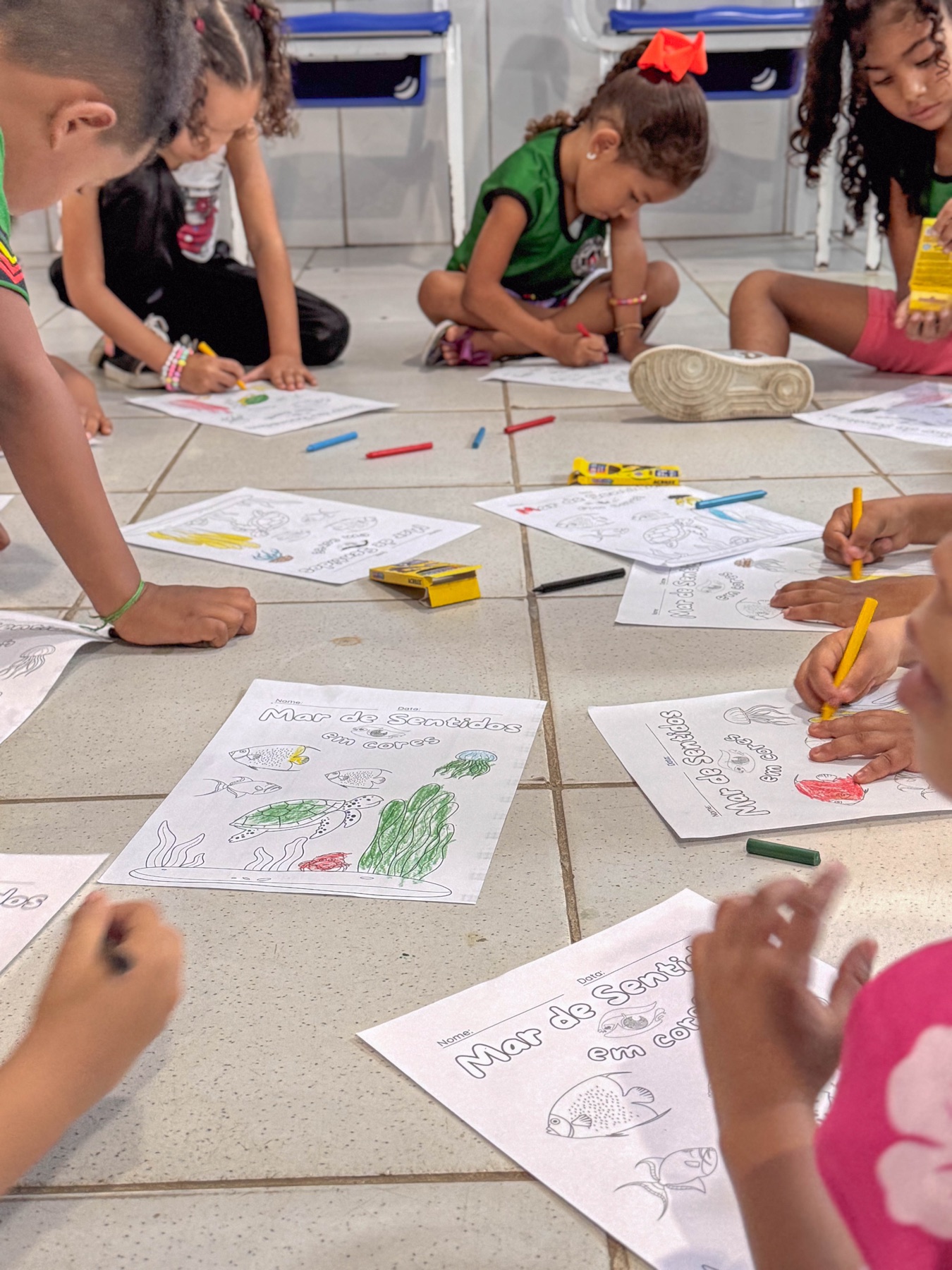 Crianças reunidas participam de uma atividade de desenho e pintura sobre o mar