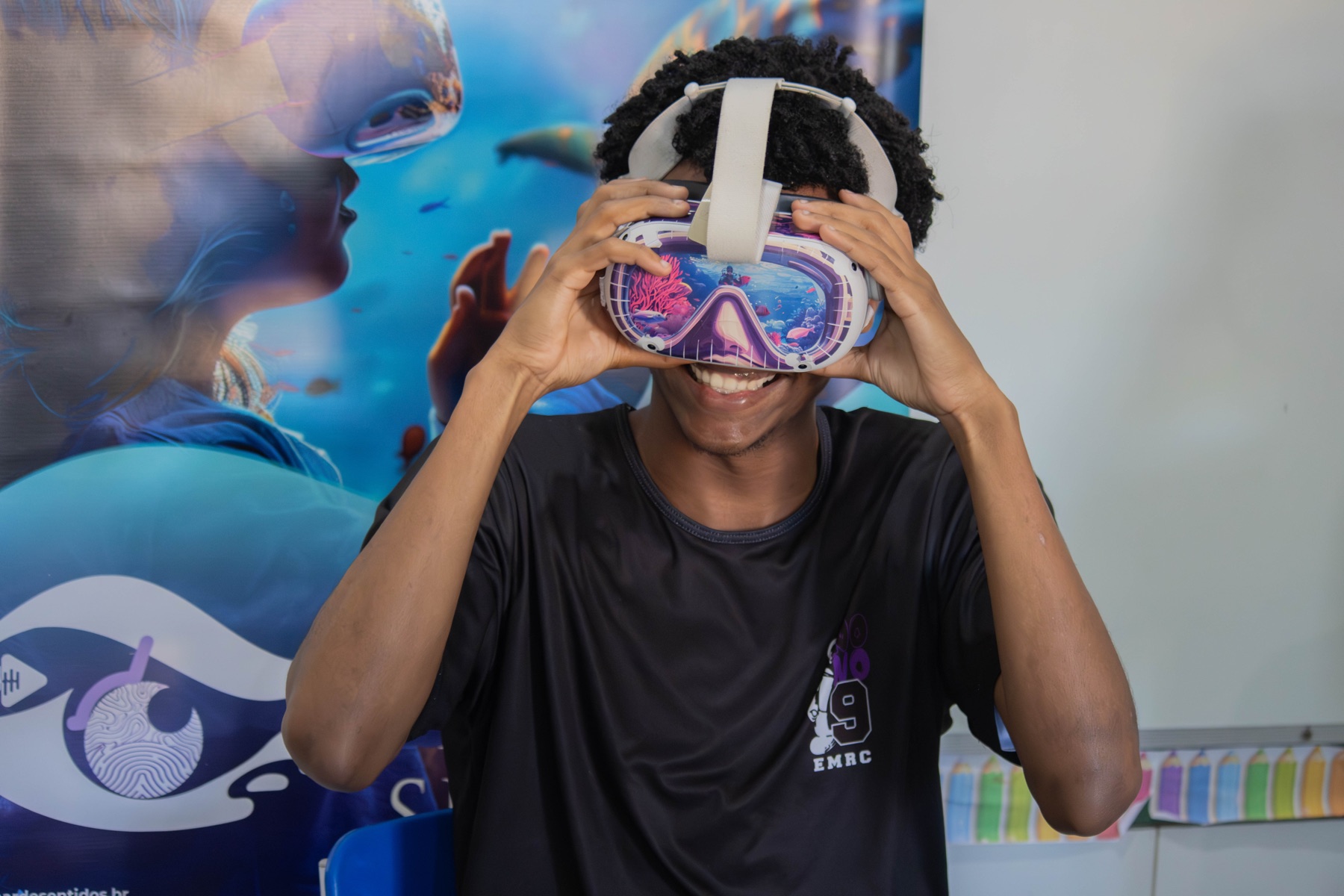 Jovem sorri enquanto utiliza óculos de realidade virtual do Projeto Mar de Sentidos