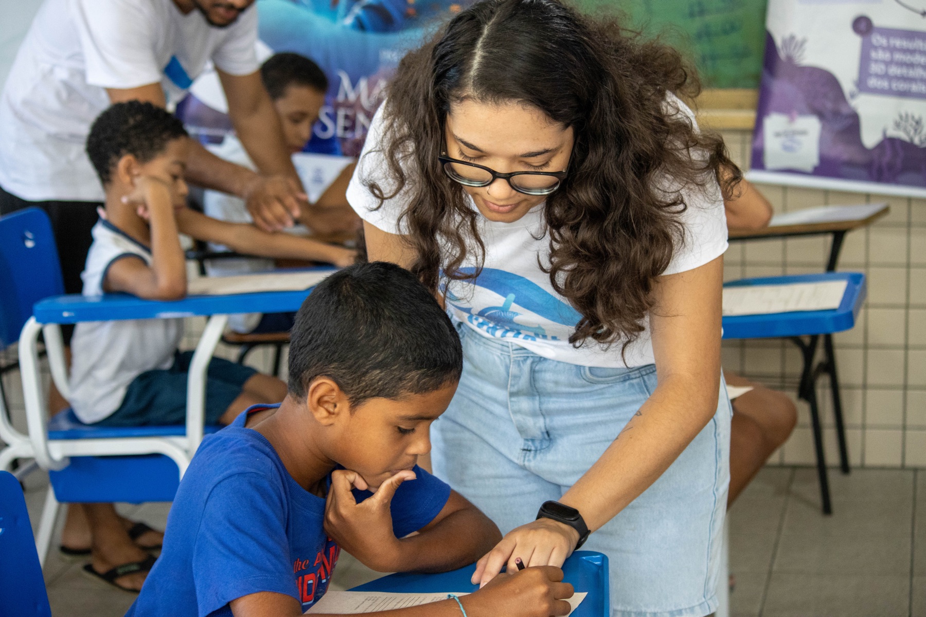Mediadora acompanha estudante durante atividade educativa em sala de aula