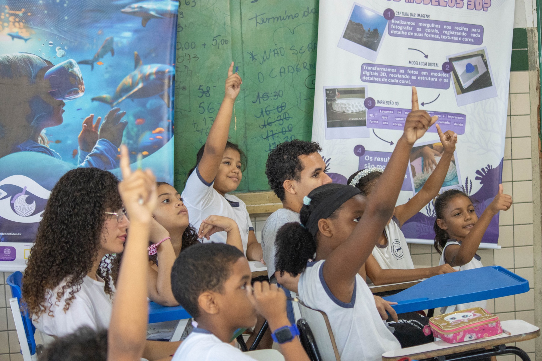 Estudantes levantam as mãos durante uma conversa sobre corais e impressão 3D