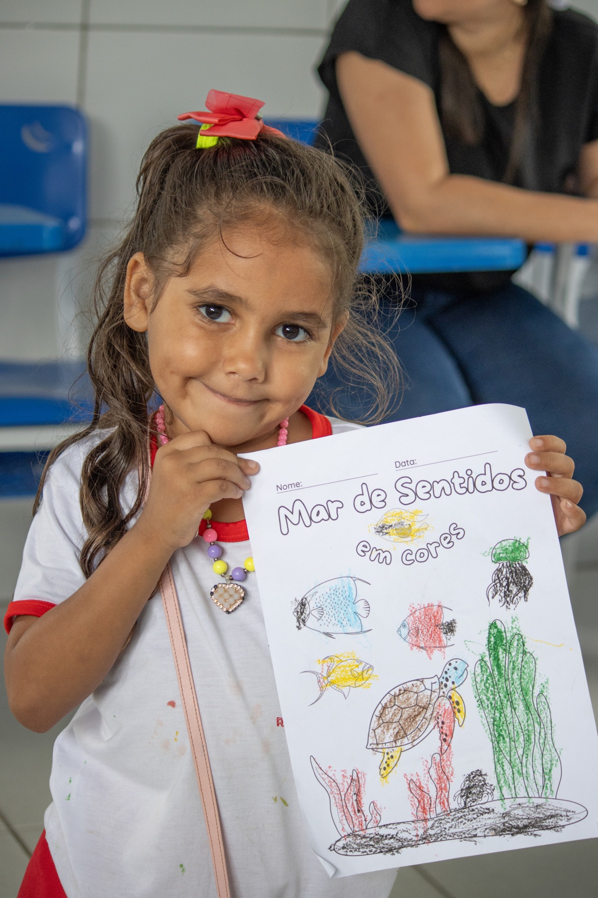 Criança mostra orgulhosa seu desenho colorido sobre a vida no fundo do mar